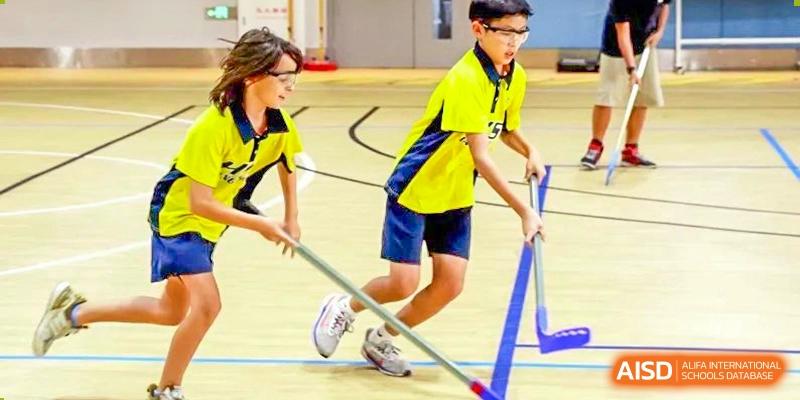 Two students from Hangzhou International School wearing yellow jerseys and playing floor hockey.