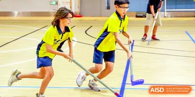 Two students from Hangzhou International School wearing yellow jerseys and playing floor hockey.