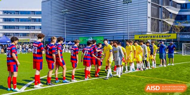 Teams from Hangzhou International School, one in red and one in yellow, lined up on a soccer field.