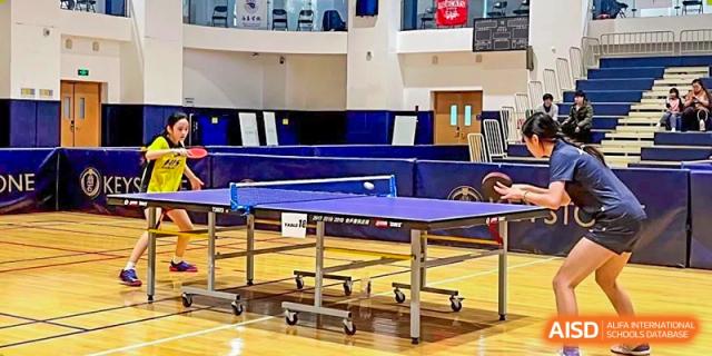 An indoor table tennis court setup with a blue ping pong table at Hangzhou International School.