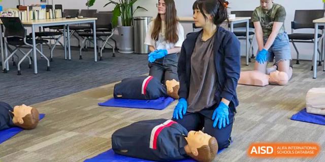 A student from Hangzhou International School practicing CPR on a training dummy during a first aid class.