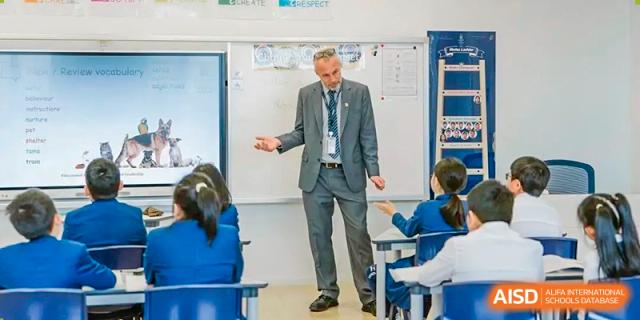 An adult teacher gesturing while instructing students in a classroom at Harrow LiDe School Chongqing (AISL Harrow Chongqing).