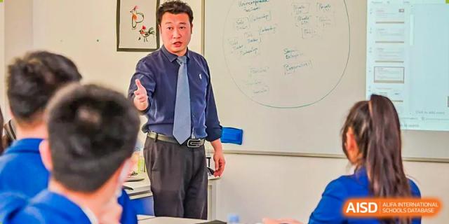 A male teacher standing in front of a whiteboard, instructing students in a classroom at Harrow LiDe School Chongqing (AISL Harrow Chongqing).