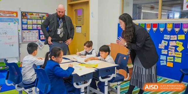 Young students at Harrow LiDe School Chongqing (AISL Harrow Chongqing) working on a group activity around a table with an instructor observing.