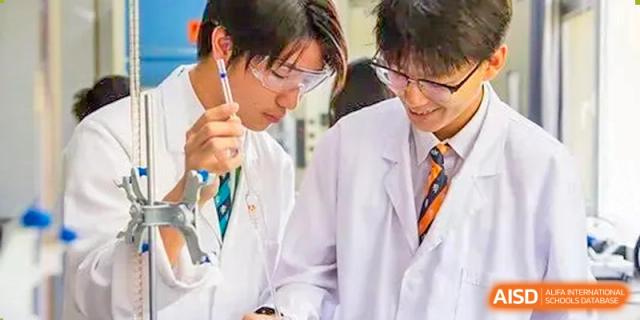 Two students from Harrow LiDe School Chongqing (AISL Harrow Chongqing) wearing lab coats and collaborating on a science experiment.
