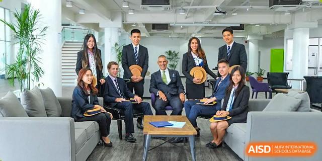 A group of staff and students from Harrow LiDe School Chongqing (AISL Harrow Chongqing), some in suits and ties, sitting around a coffee table for a meeting or photo opportunity.