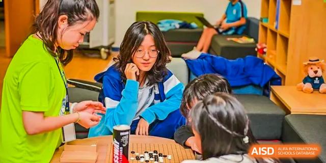 A student at Harrow LiDe School Chongqing (AISL Harrow Chongqing) thoughtfully considering a move while playing the board game Go with other students.