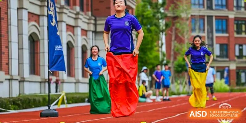 Students from Harrow LiDe School Chongqing (AISL Harrow Chongqing) participating in a sack race on a red track during a sports day event.