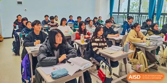 Close-up of a diverse group of students sitting at desks, facing forward and engaged in a class discussion or lecture Hefei No.6 High School International Department.
