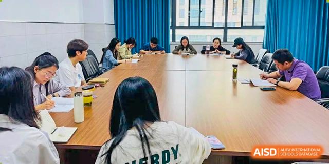A student viewed from behind, sitting with a group of other students around a table in a discussion setting Hefei No.6 High School International Department.