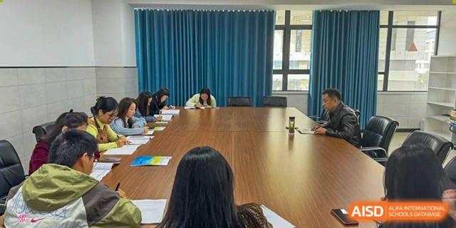 Students and faculty sitting around a large, polished wooden table in a meeting or conference room Hefei No.6 High School  International Department.
