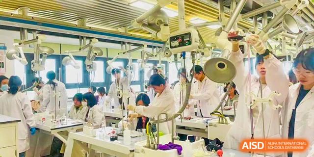 Students in white lab coats actively working with complex equipment and materials in a science laboratory setting Hefei No.6 High School International Department.