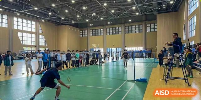 Students engaging in a badminton class or game inside the spacious, well-lit indoor gymnasium at the Hefei No.6 High School  International Department.
