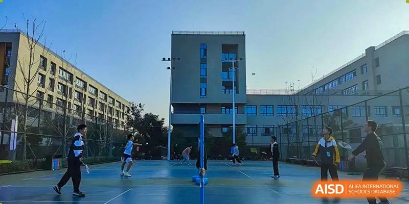 Students playing volleyball on an outdoor court set up near the modern school building at the  Hefei No.6 High School International Department.