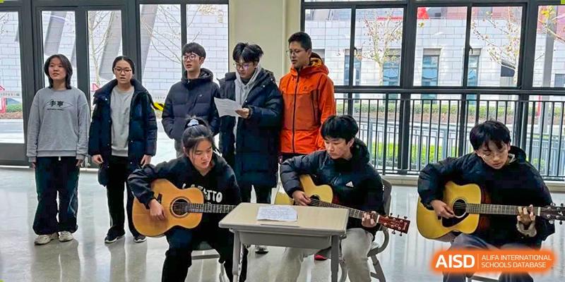 Two students playing acoustic guitars and singing during an informal music or cultural activity at the Hefei No.6 High School International Department.
