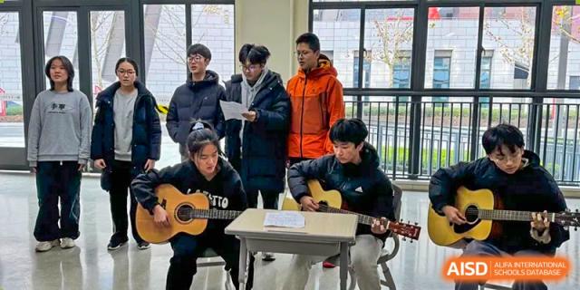 Two students playing acoustic guitars and singing during an informal music or cultural activity at the Hefei No.6 High School International Department.