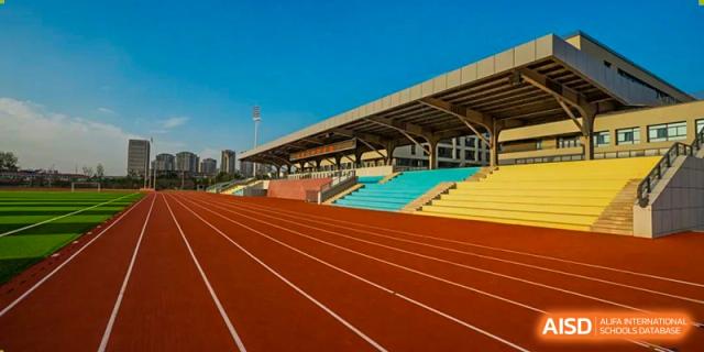 The outdoor running track and stadium seating in bright red, blue, and yellow, highlighting the athletic facilities at the Hefei No.6 High School International Department.