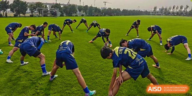 Students performing warm-up stretches or exercises together on a grassy field as part of a sports team practice at the Hefei No.6 High School  International Department.
