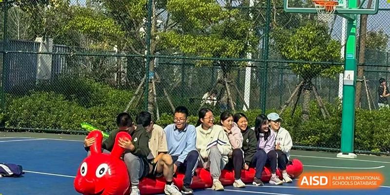 A group of students laughing and engaging in a teamwork activity or game outdoors on the campus of the Hefei No.6 High School  International Department.