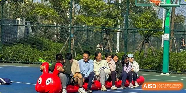 A group of students laughing and engaging in a teamwork activity or game outdoors on the campus of the Hefei No.6 High School  International Department.