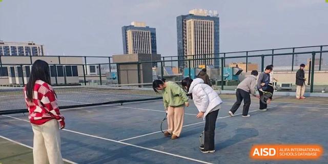 Students participating in a game or activity on an outdoor tennis or sports court on the rooftop or upper level of the school campus at the  Hefei No.6 High School International Department.