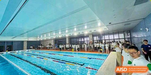 A large group of students and staff standing by the indoor swimming pool, likely before or after an event or training session at the Hefei No.6 High School  International Department.