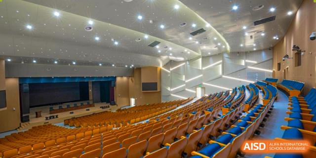The spacious, modern auditorium or lecture hall, featuring rows of empty orange seating and professional lighting at the Hefei No.6 High School International Department.