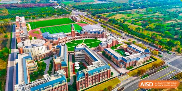 An aerial view of the expansive Hiba Academy Nantong campus, showing its red-brick buildings, sports fields, and well-maintained green spaces.
