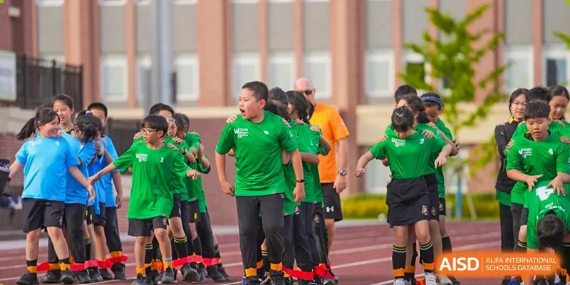 Students from Hiba Academy Nantong, dressed in green and orange sports uniforms, standing on a track or field, possibly preparing for a competition.
