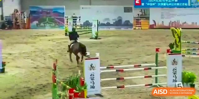 A student riding a horse over hurdles in an equestrian jumping competition or practice at Kunming International Academy.