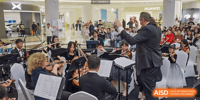 Students playing instruments as part of an orchestra or musical ensemble with a conductor visible at Kunming International Academy.