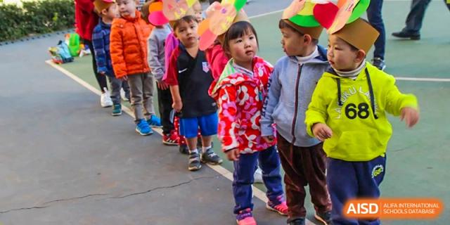 Young students in colorful coats and hats lining up outdoors, potentially for a field day or event at Kunming International Academy.