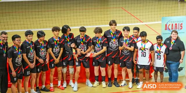 A boys' volleyball team standing side-by-side, wearing medals after a tournament victory at Kunming International Academy.