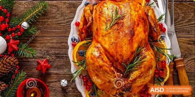 A beautifully photographed roasted turkey garnished with rosemary and orange slices on a wooden platter, symbolizing a festive Thanksgiving celebration or meal at Kunming International Academy.