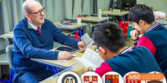A close-up view of two students from Milton International School Qingdao collaboratively studying or reading the same book at a shared desk.