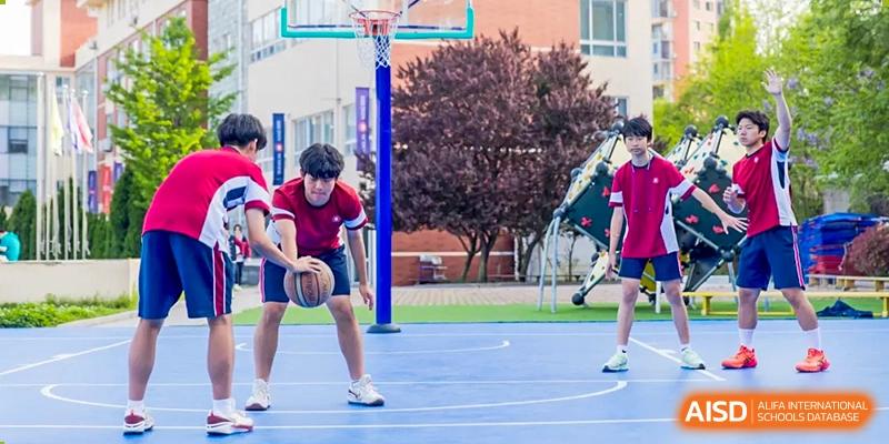 Students playing basketball outdoors on a blue court during a sports activity at Milton International School Qingdao.