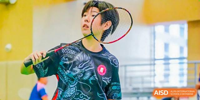 Student concentrating while holding a badminton racket during a sports class at Milton International School Qingdao.