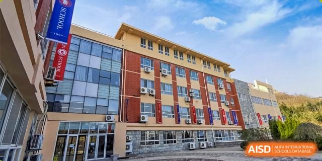 Exterior view of the main academic building with large windows under a blue sky at Milton International School Qingdao.
