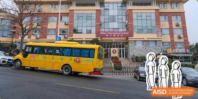 The exterior of the main building at Milton International School Qingdao with a distinctive yellow school bus parked on the street in front of the entrance.