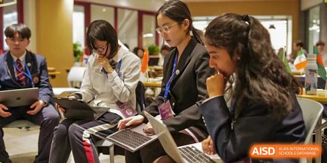 A close-up of Nanjing International School students and adults collaborating around laptops during a professional or academic discussion.