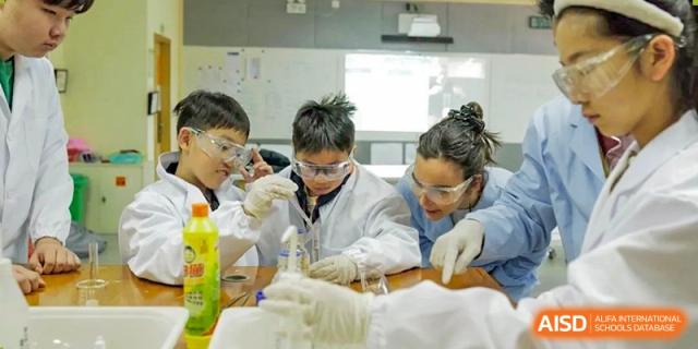 A wide shot of Nanjing International School students in lab coats working in a clean, brightly lit science laboratory.