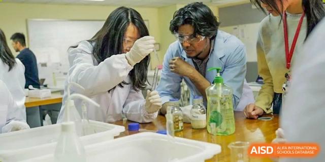 A Nanjing International School teacher assists a student in a science lab during a chemistry experiment.