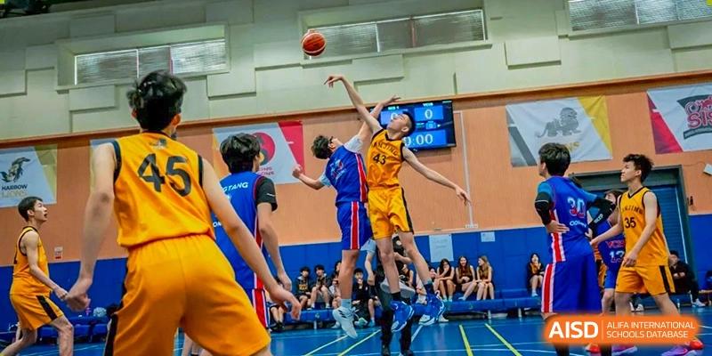 Two Nanjing International School basketball players jumping to contest a shot near the basket with a score clock visible.