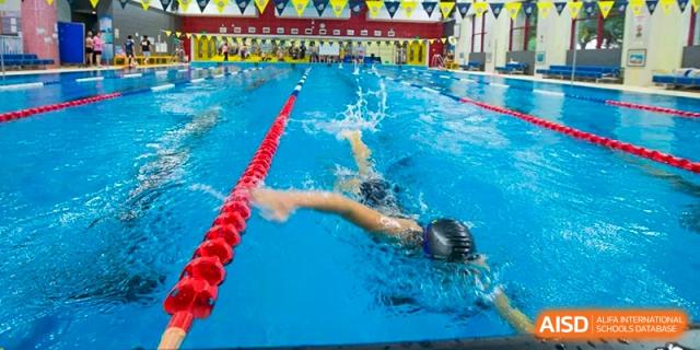 An action shot of a Nanjing International School swimmer doing the backstroke in a competition lane.