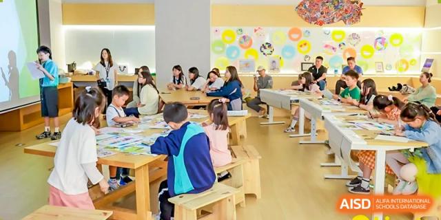 Young Nord Anglia Chinese International School Shanghai students working independently at small wooden desks in a bright classroom setting.