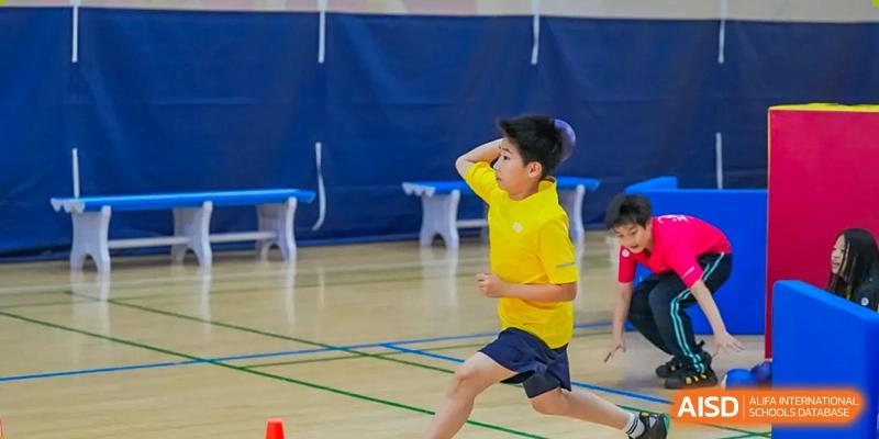 A Nord Anglia Chinese International School Shanghai student in a yellow shirt running quickly during an indoor sports activity.