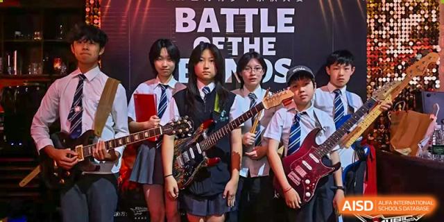 A group of Nord Anglia Chinese International School Shanghai students in a band posing with their guitars and instruments in front of a "Battle of the Bands" banner.
