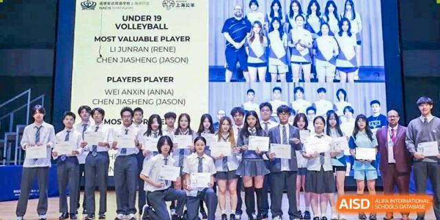A large group of Nord Anglia Chinese International School Shanghai students dressed in school uniforms posing for a photo with a banner celebrating volleyball players.