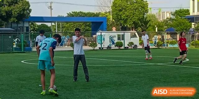 A Nord Anglia Chinese International School Shanghai student doing a stretching exercise on a green outdoor sports field.