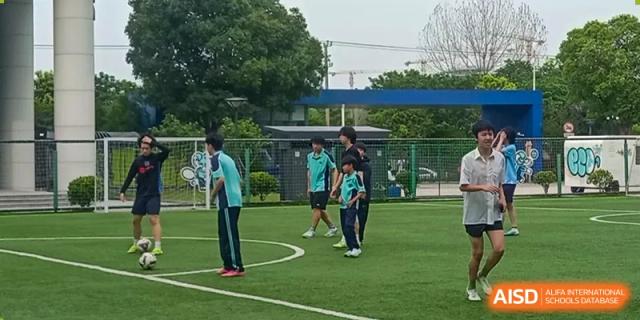 Nord Anglia Chinese International School Shanghai students playing soccer on a green turf field during an outdoor sports activity.